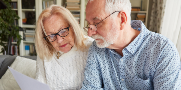 Een senior echtpaar bekijkt aandachtig documenten, met een serieuze en geconcentreerde uitdrukking.